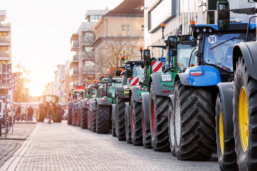 Farmers union protest strike against government Policy in Germany Europe. Tractors vehicles blocks city road traffic. Agriculture farm machines Magdeburg central Domplatz square